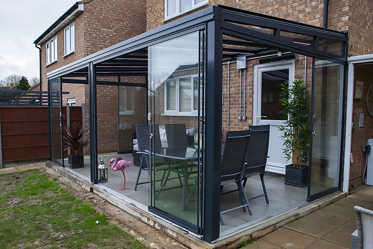 Modern glass garden room veranda with outdoor dining set attached to a brick house