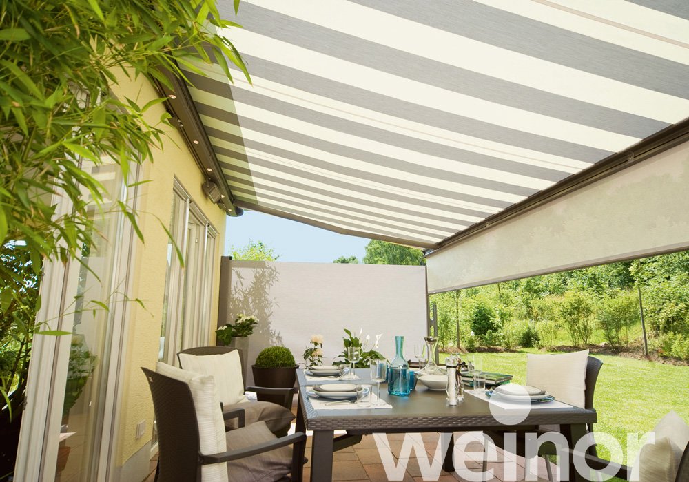 Modern garden patio with striped retractable awning, elegant dining set, and outdoor greenery