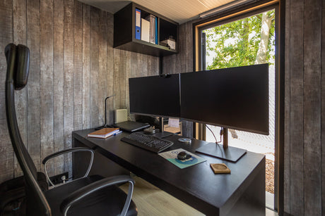 Modern home office setup with dual monitors, ergonomic chair, and garden view through window
