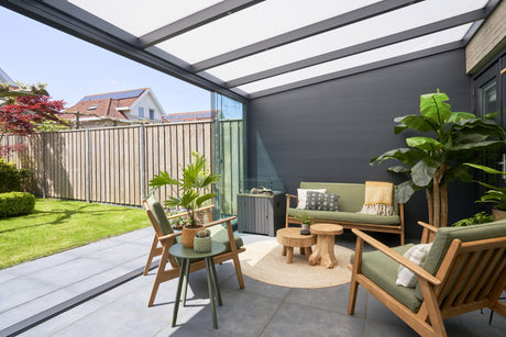 Modern garden veranda with green seating, wooden tables, and lush plants under a sleek canopy