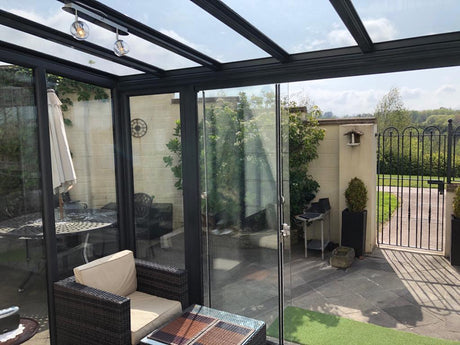 Modern glass veranda with cozy seating, outdoor dining, and garden views for elegant outdoor living