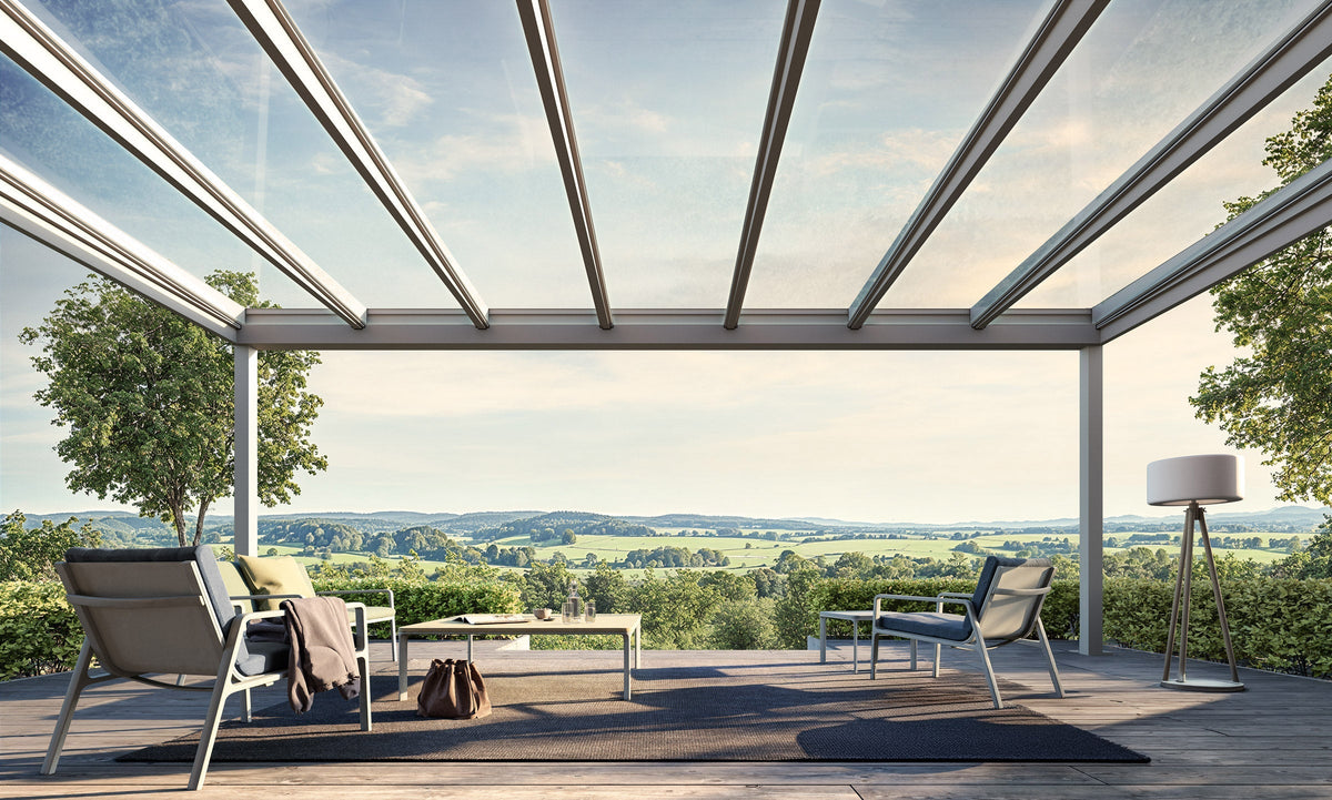 Modern glass-roofed veranda with cozy seating overlooking scenic green hills