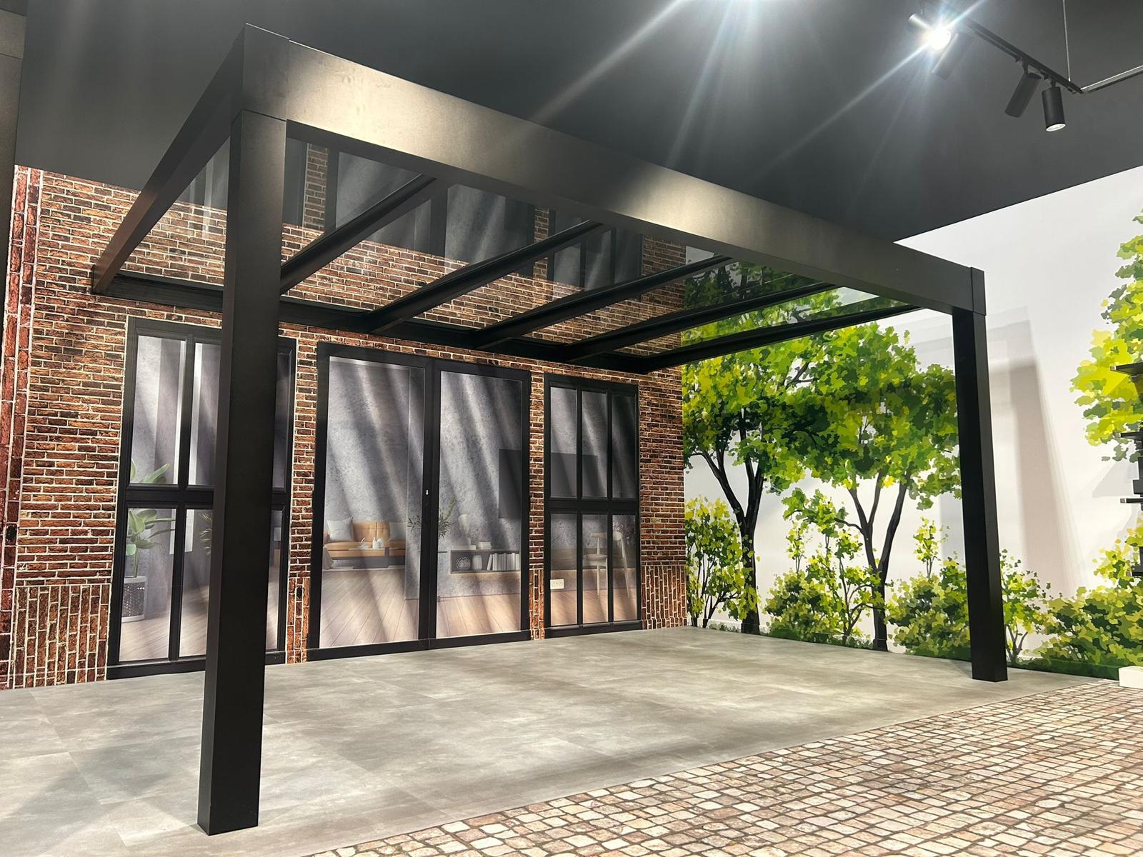 Modern black metal pergola with glass roof over brick patio, ideal for outdoor living spaces and garden rooms