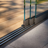 modern sliding glass door track system on outdoor patio with wood and stone flooring