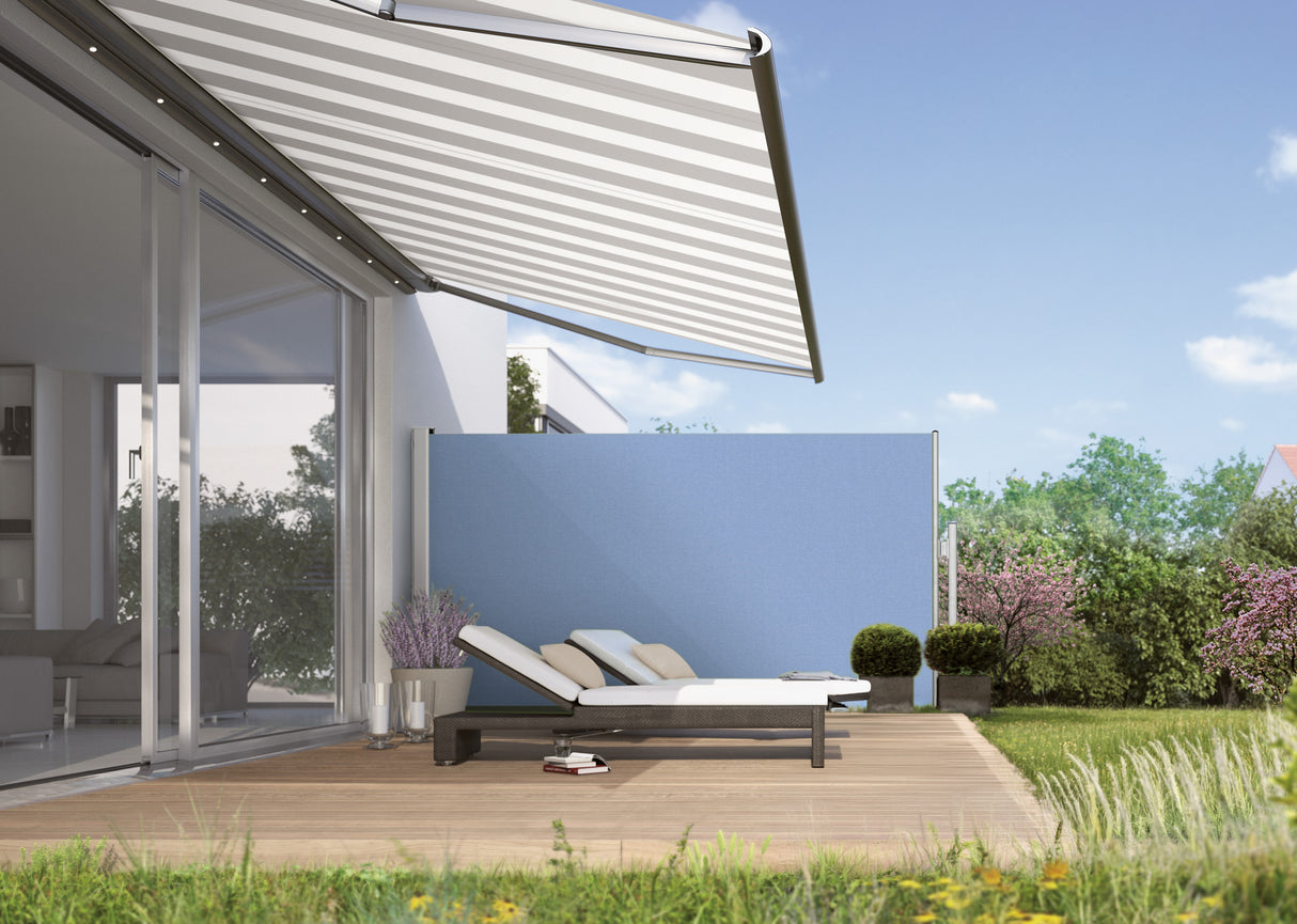 Modern patio with retractable awning, privacy screen, and sun loungers in a garden setting