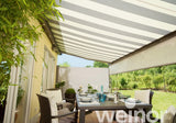 Modern garden patio with striped retractable awning, elegant dining set, and outdoor greenery